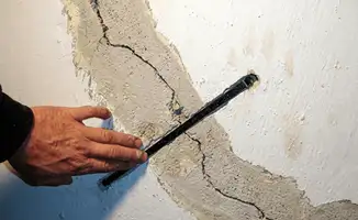 A wall with a large crack is being inspected by a professional in Philadelphia, PA
